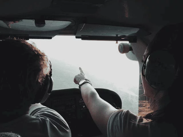 un homme et une femme dans le cockpit d'un hélicoptère. La femme montre le chemin.